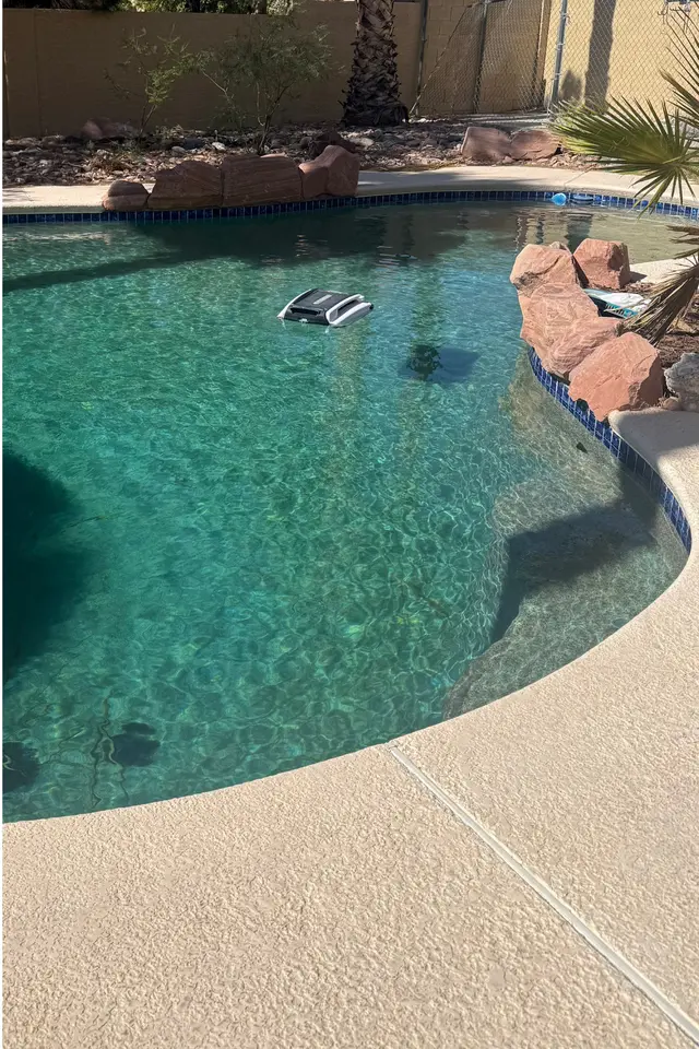 The same pool with clear water and a robotic cleaner floating on it