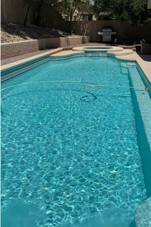 The same pool with clear blue water, the spa and steps visible