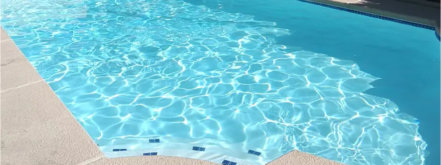 The same pool with clear blue water and its tiled steps visible